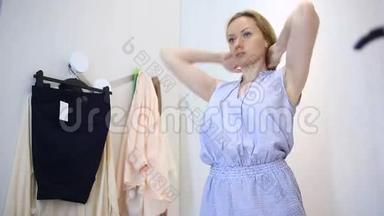 女人在服装店购物，挑选衣服，女人在更衣室试穿衣服，照镜子